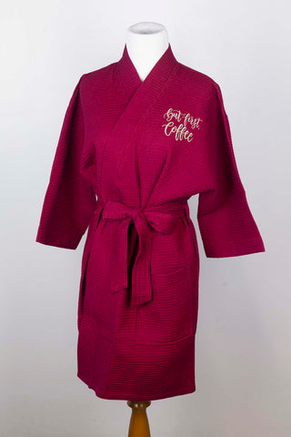 Detail of wine-colored robe featuring "But first, coffee" in latte-colored script text on a bodyform.