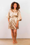 Woman wearing a taupe satin robe.